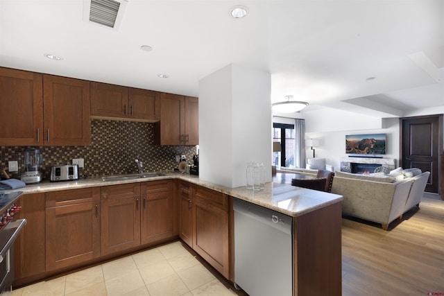 kitchen featuring sink, dishwasher, backsplash, light stone countertops, and kitchen peninsula