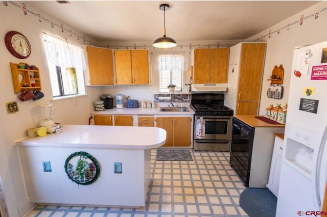 kitchen featuring a healthy amount of sunlight, gas stove, white fridge with ice dispenser, and kitchen peninsula