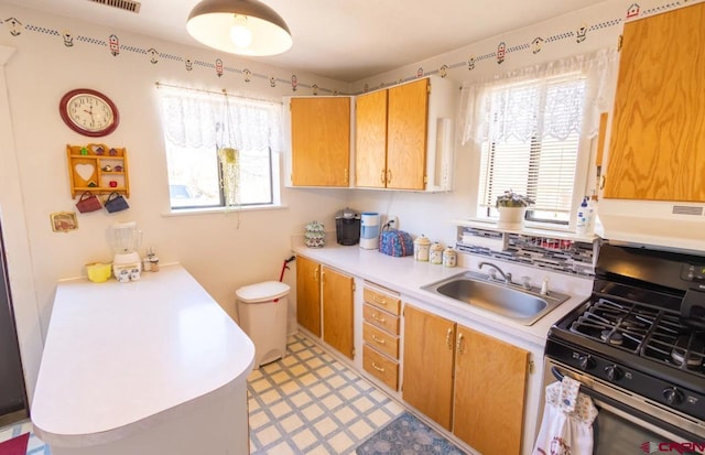 kitchen with sink, plenty of natural light, range with gas cooktop, and light tile floors