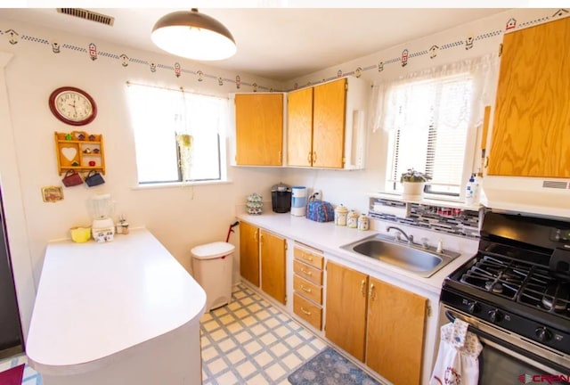 kitchen featuring sink, range with gas cooktop, plenty of natural light, and light tile floors