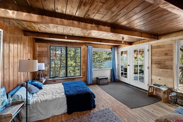 bedroom featuring hardwood / wood-style flooring, wooden ceiling, beamed ceiling, wooden walls, and french doors