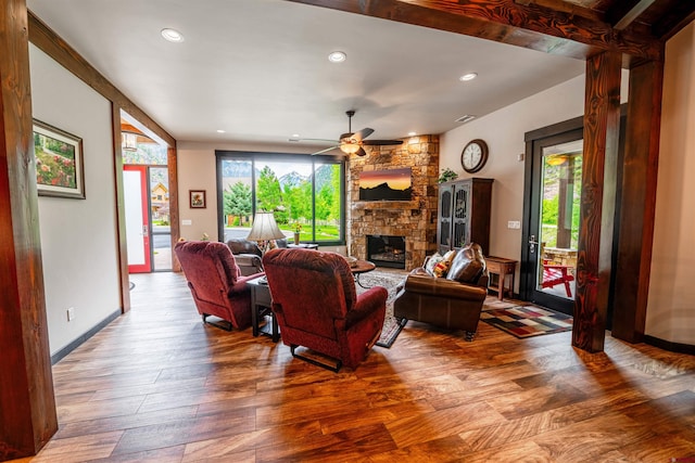 living room featuring beam ceiling, a fireplace, ceiling fan, and hardwood / wood-style floors