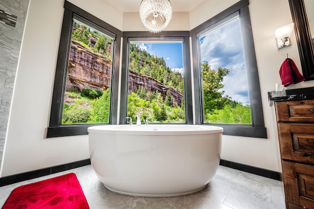 bathroom with a healthy amount of sunlight, a notable chandelier, and tile floors