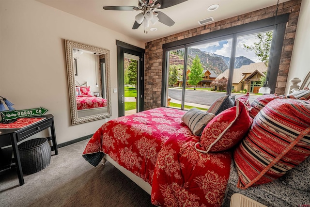 carpeted bedroom with ceiling fan, access to exterior, a mountain view, and brick wall