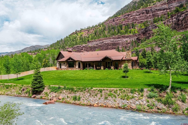 view of front of home with a water and mountain view and a front lawn