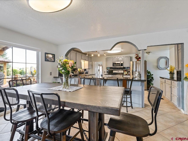 tiled dining room featuring a textured ceiling and track lighting