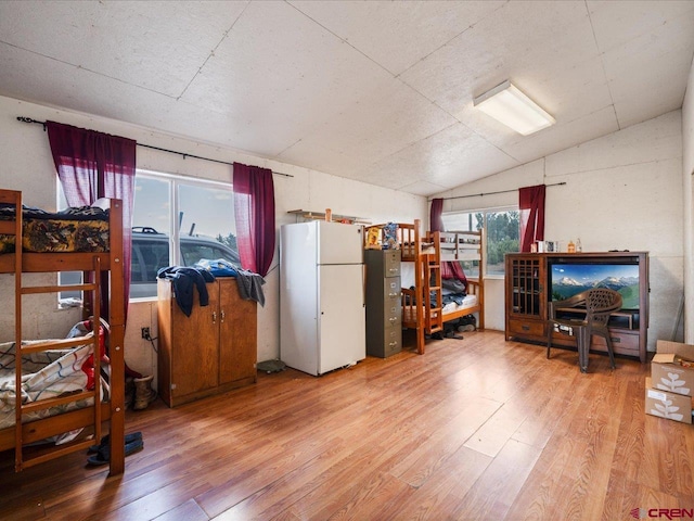 interior space featuring white refrigerator, vaulted ceiling, and hardwood / wood-style flooring