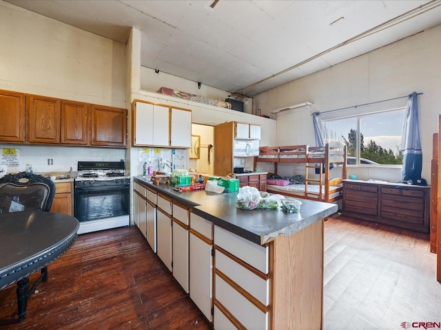 kitchen with hardwood / wood-style floors, sink, white range with gas cooktop, and kitchen peninsula