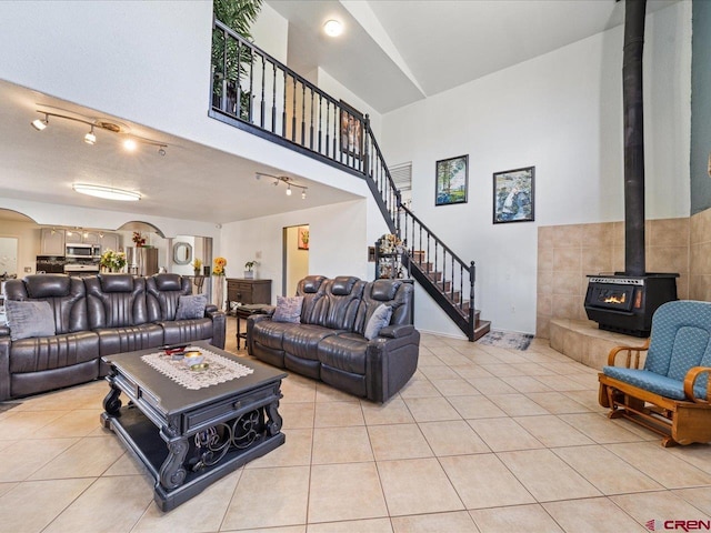 living room featuring track lighting, a wood stove, and light tile floors