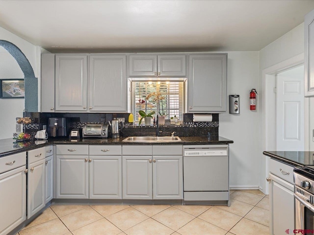 kitchen with sink, backsplash, white dishwasher, and light tile floors