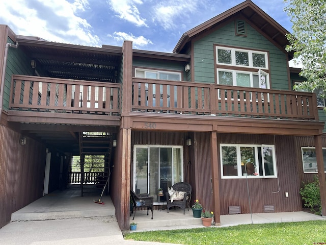 back of property with a balcony, a patio, and a wooden deck