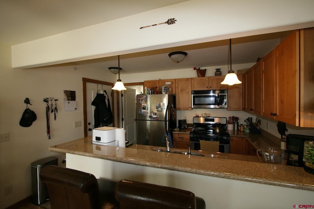 kitchen with stainless steel appliances, a kitchen breakfast bar, light stone counters, kitchen peninsula, and decorative light fixtures