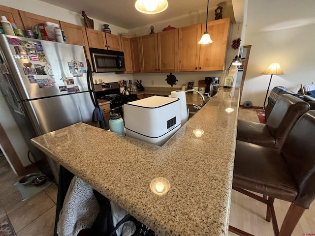 kitchen featuring light stone countertops, stainless steel appliances, a kitchen breakfast bar, kitchen peninsula, and pendant lighting