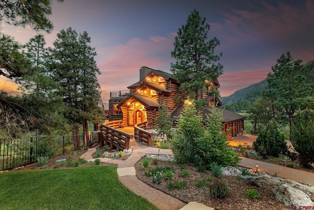 view of front of home featuring a lawn, a mountain view, and a balcony