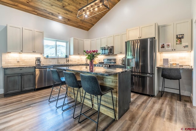 kitchen with a breakfast bar, wooden ceiling, high vaulted ceiling, a kitchen island, and stainless steel appliances