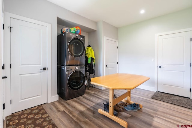 laundry area with hardwood / wood-style floors and stacked washer and clothes dryer