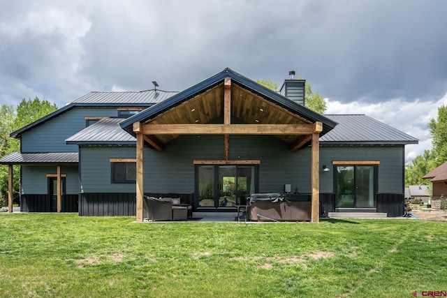 back of property featuring a lawn, a patio, and a hot tub