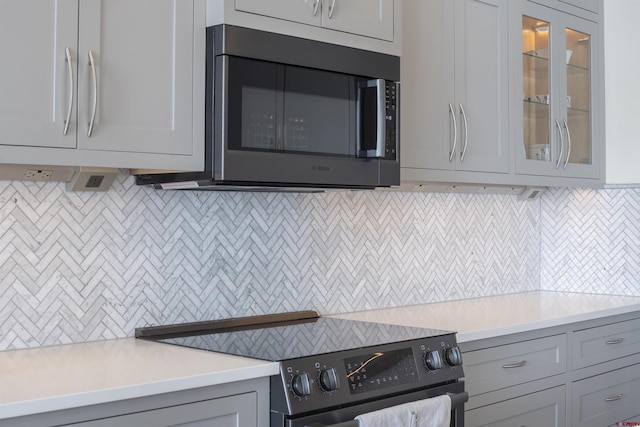 kitchen featuring gray cabinets, backsplash, and black / electric stove