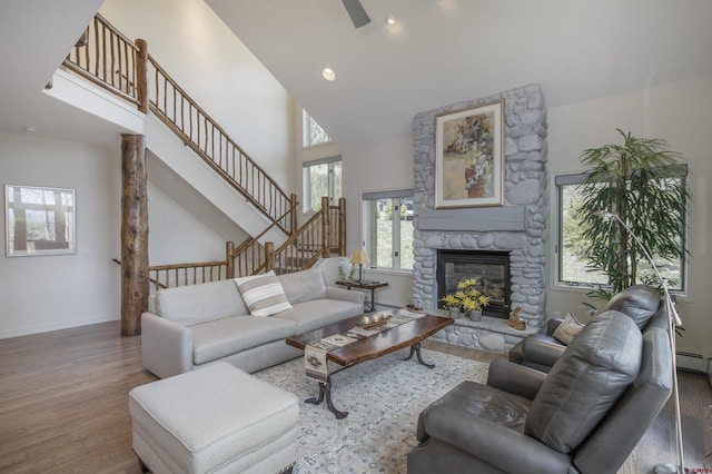 living room with wood-type flooring, high vaulted ceiling, a stone fireplace, and ceiling fan