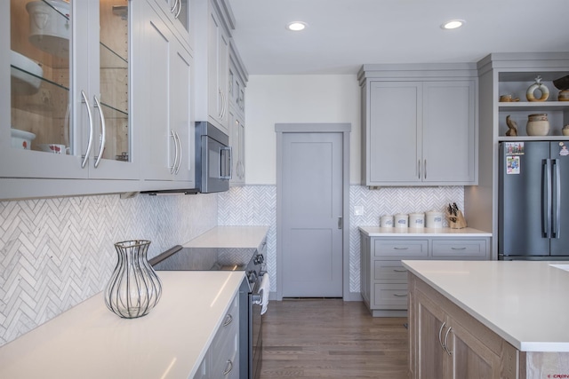 kitchen featuring backsplash, gray cabinetry, dark hardwood / wood-style flooring, and appliances with stainless steel finishes