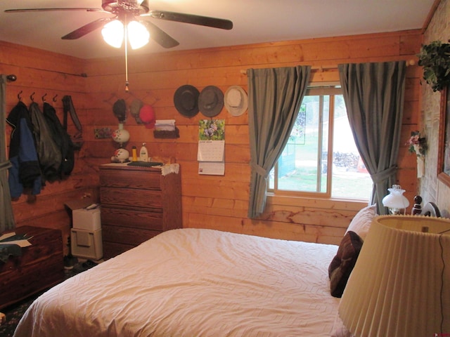 bedroom featuring ceiling fan and wood walls