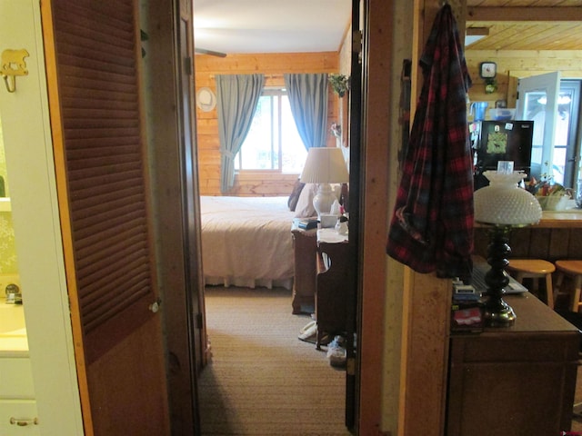 hallway featuring carpet and wood walls