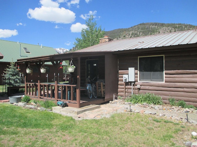 back of house with a mountain view and a lawn