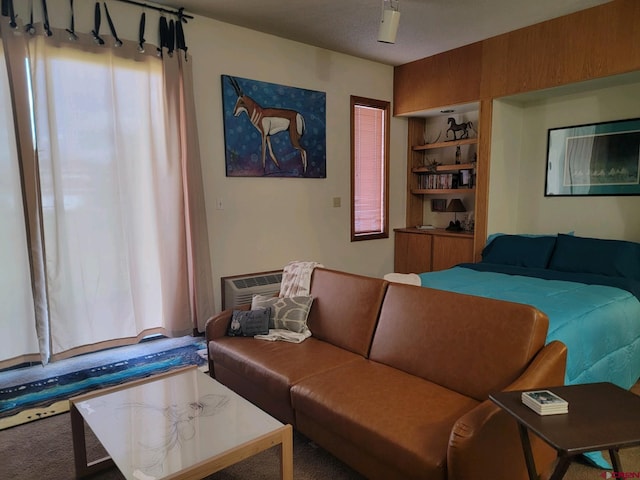 living room with an AC wall unit, built in features, and carpet floors