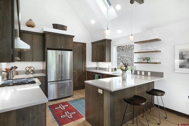 kitchen with a peninsula, a skylight, freestanding refrigerator, dark brown cabinets, and light wood-type flooring