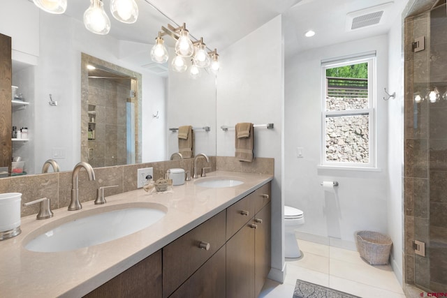 bathroom featuring tile flooring, oversized vanity, double sink, a tile shower, and toilet