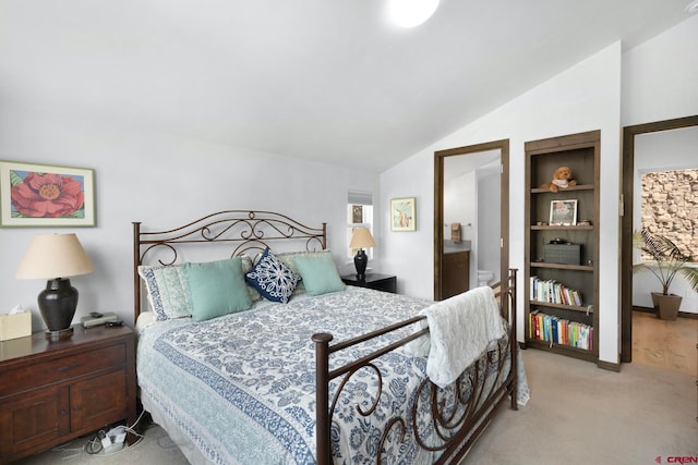 bedroom featuring ensuite bathroom, carpet floors, and vaulted ceiling