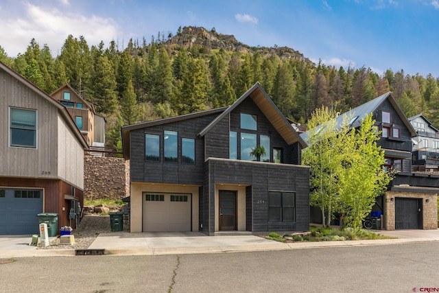 view of front of home with driveway, a view of trees, and a garage