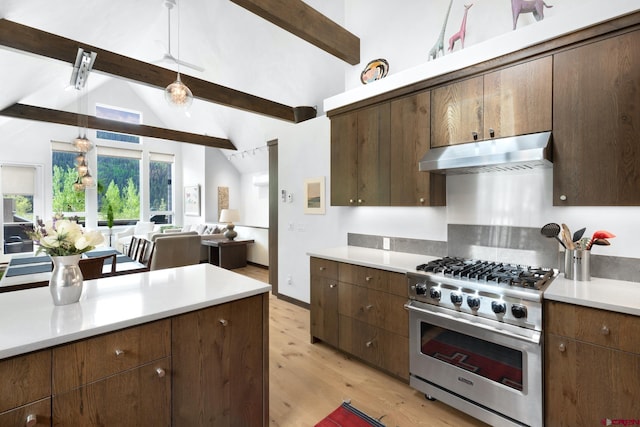 kitchen featuring light wood-style flooring, under cabinet range hood, lofted ceiling with beams, light countertops, and high end range