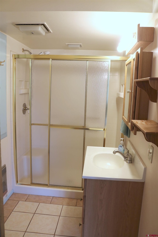 bathroom with a shower with shower door, vanity, and tile floors