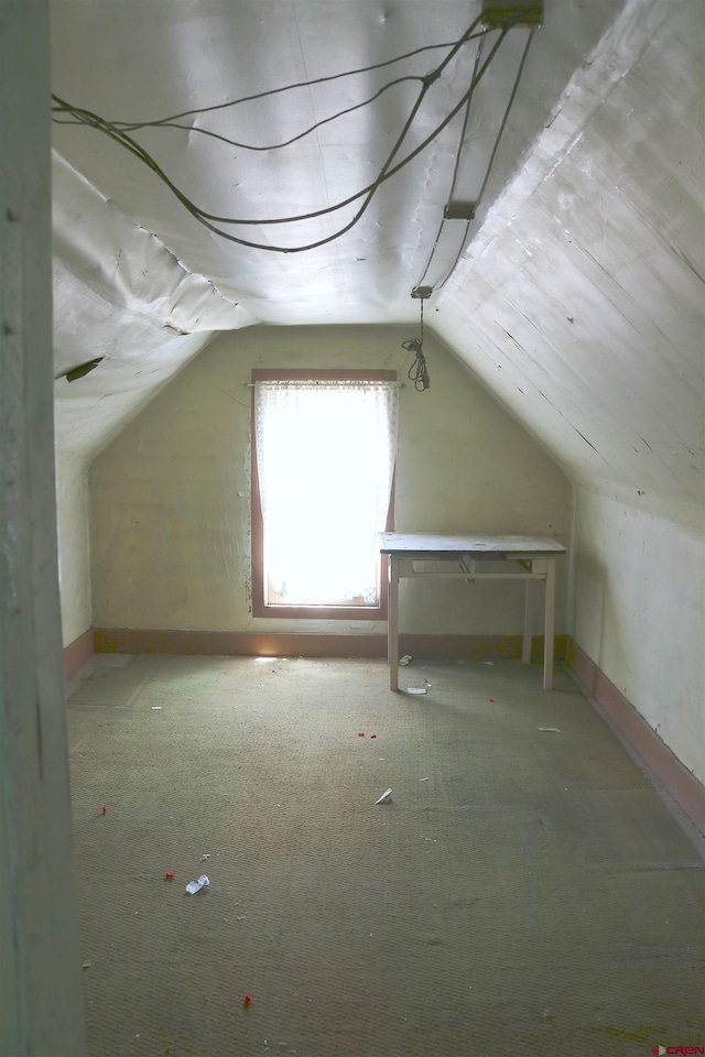 additional living space featuring vaulted ceiling and carpet flooring