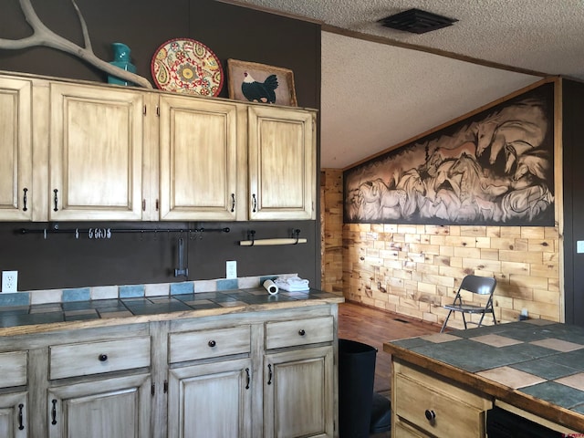 kitchen with wood-type flooring, tile counters, and a textured ceiling