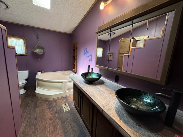 bathroom featuring vaulted ceiling, wood-type flooring, a bathtub, a textured ceiling, and toilet