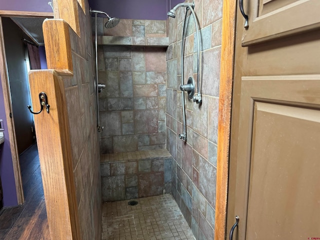 bathroom featuring a tile shower and wood-type flooring