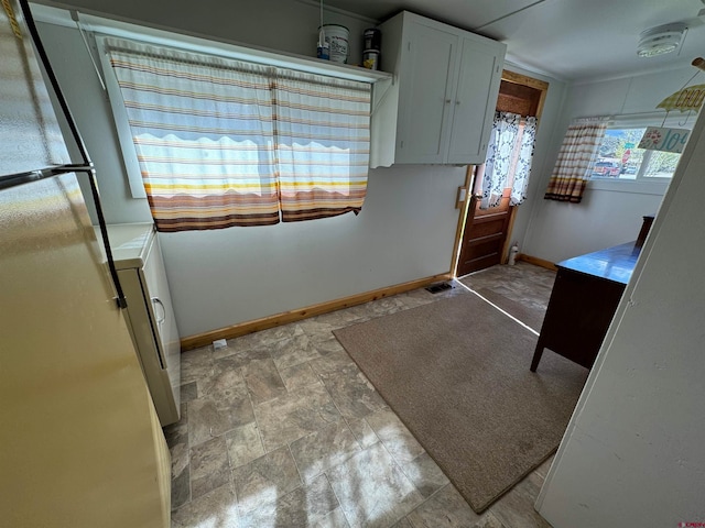 kitchen featuring washer / dryer, white cabinets, stainless steel fridge, and tile floors