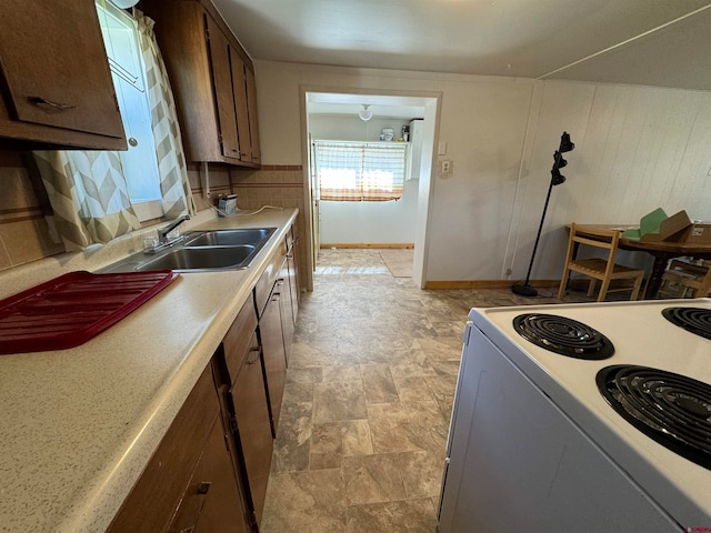 kitchen with dark brown cabinets, range, backsplash, light tile floors, and sink