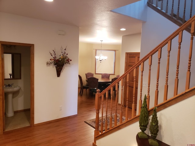 stairway featuring sink, an inviting chandelier, and hardwood / wood-style flooring