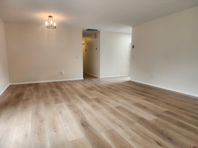 unfurnished room with a notable chandelier and light hardwood / wood-style floors