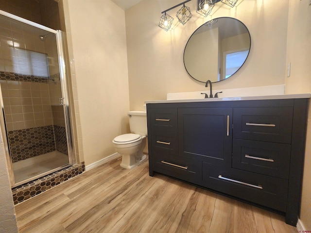 bathroom with toilet, a shower with shower door, hardwood / wood-style flooring, and vanity