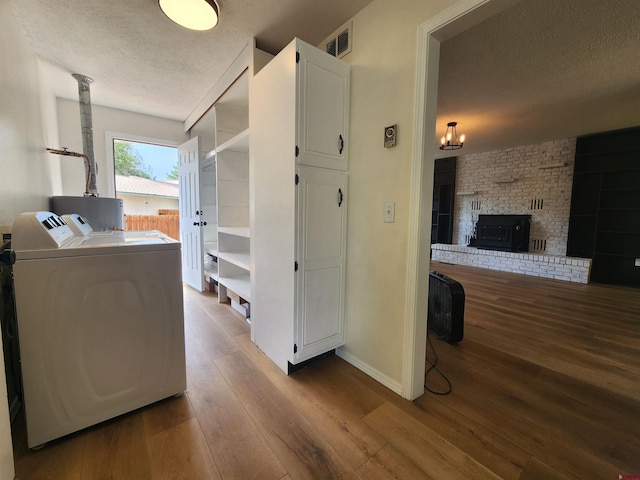 interior space featuring water heater, wood-type flooring, a textured ceiling, and independent washer and dryer