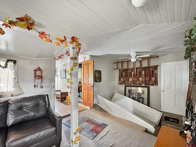 interior space with ceiling fan, carpet floors, wooden walls, and lofted ceiling