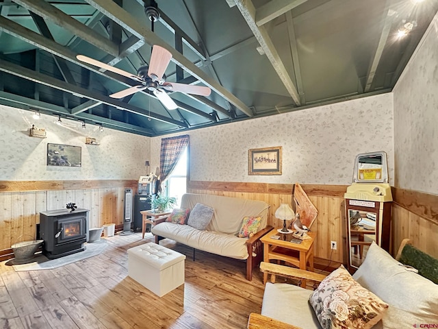 living room with hardwood / wood-style floors, vaulted ceiling, a wood stove, and ceiling fan