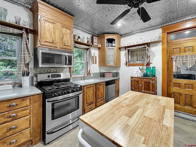 kitchen with appliances with stainless steel finishes, ceiling fan, sink, light tile patterned floors, and butcher block countertops