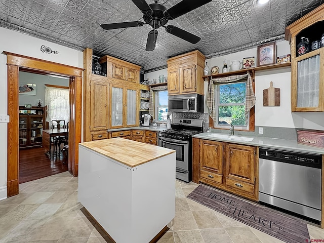 kitchen featuring appliances with stainless steel finishes, ornamental molding, ceiling fan, sink, and butcher block countertops