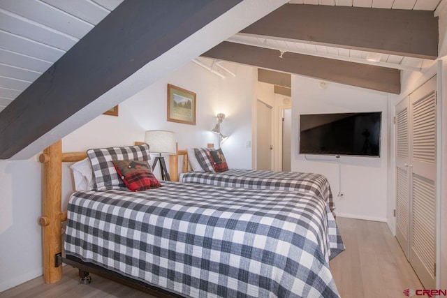 bedroom featuring lofted ceiling with beams and light wood-type flooring