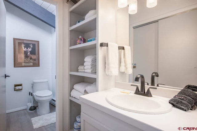 bathroom featuring built in features, a baseboard heating unit, vanity, wood-type flooring, and toilet